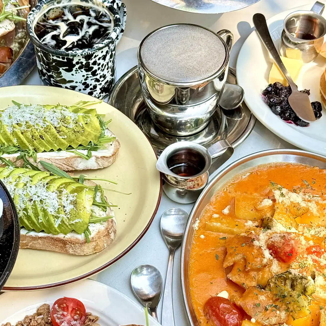 Open avocado toast, a creamy pasta and a latte on a JAM JAM table