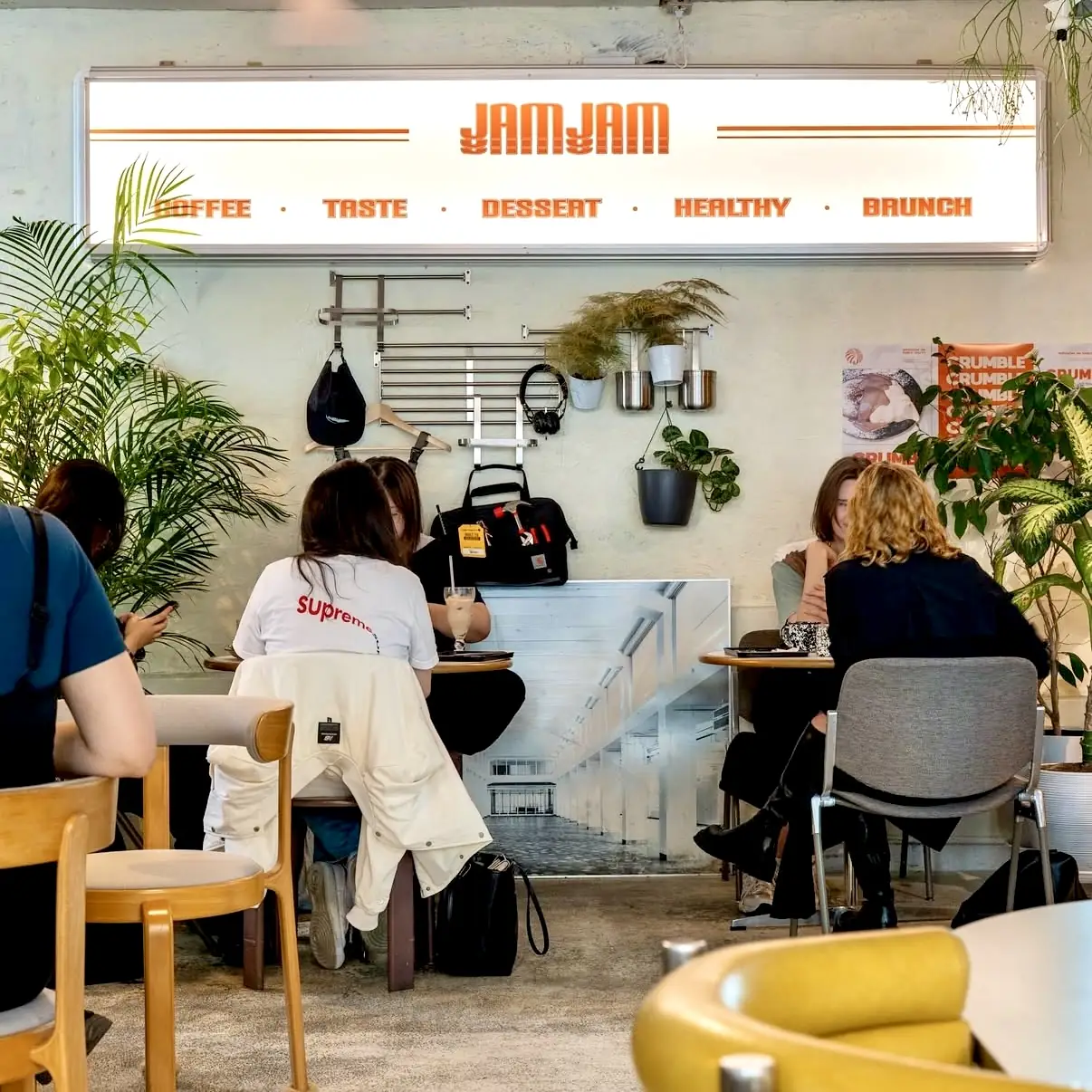 Guests on the sofa seating under the orange 'JAMJAM — Coffee · Taste · Dessert · Healthy · Brunch' sign